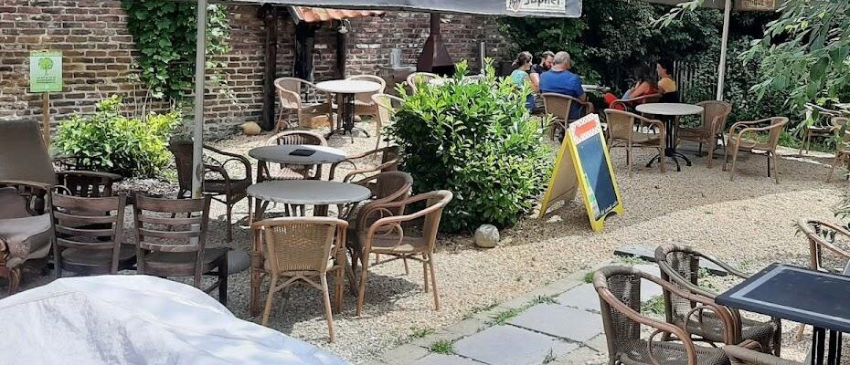 Het terras van Café Halfweg met rieten stoelen tussen het groen