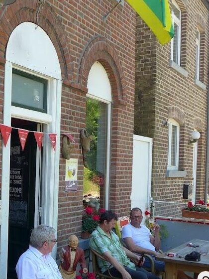 De bakstenen gevel met boogramen en gasten voor de deur